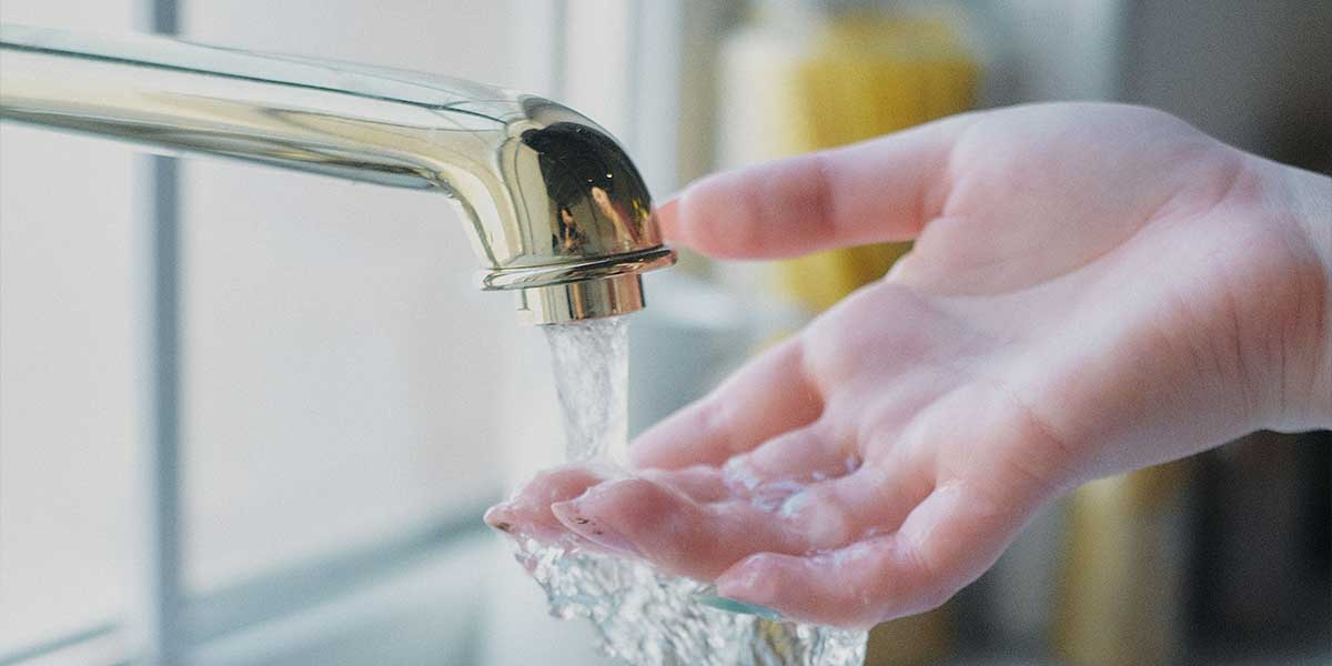 Hand filling a glass with water from a tap